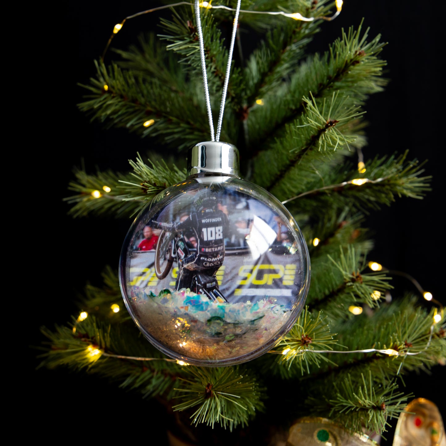 Clear Christmas ornament with a printed design on a decorated tree.